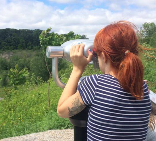 A women looks through a view finder to get a closer look at the landscape.